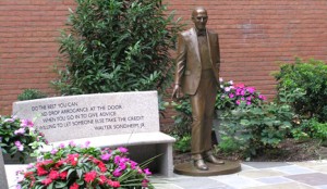 Bronze statue of Mr. Walter Sondheim for whom the Sondheim Public Affairs Scholars program is named. There is a bench with a quote from Mr. Sondheim, flowers and a brick wall