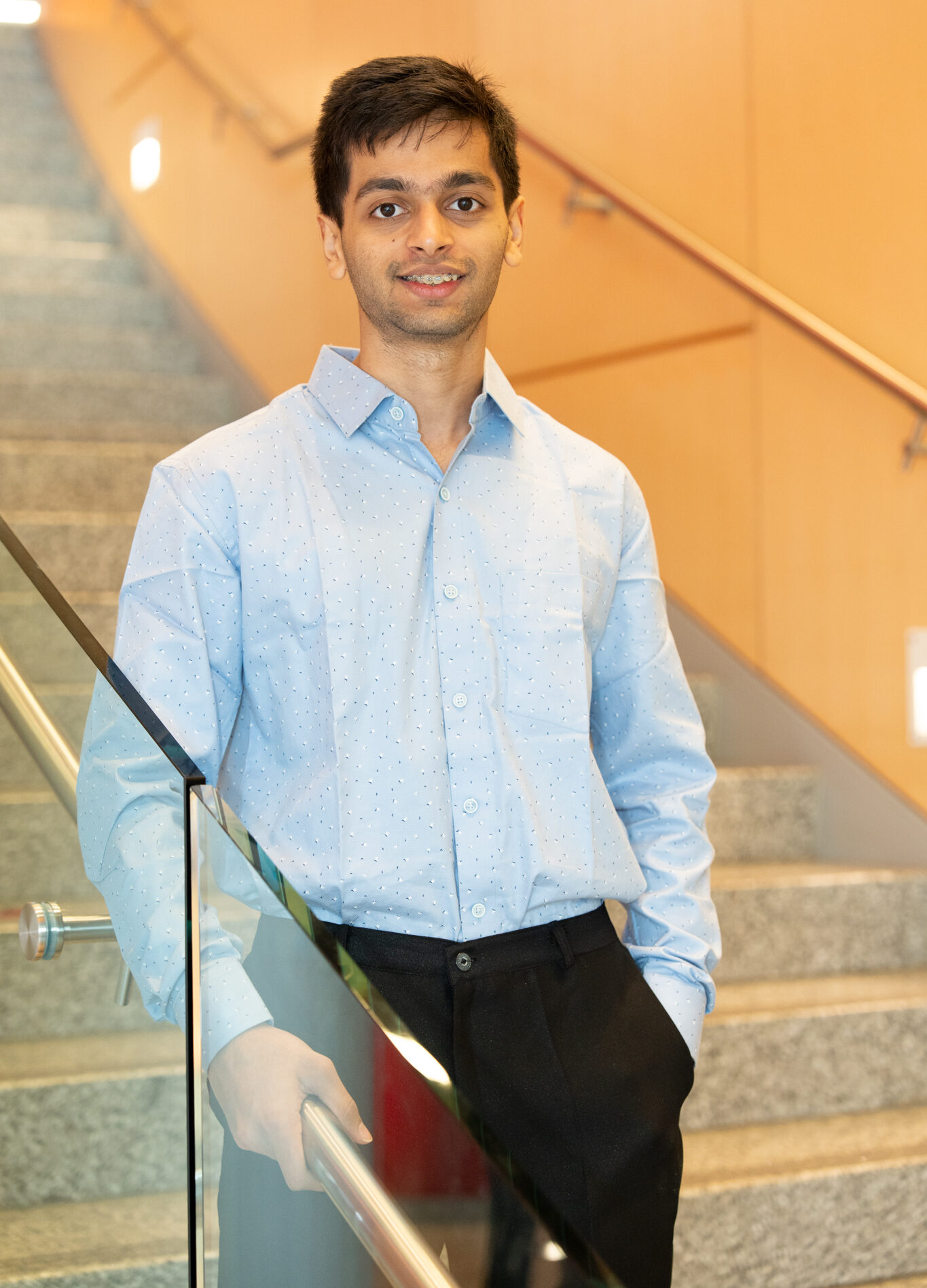 Aum Chordia on a set of stairs, wearing a light blue button-down shirt.